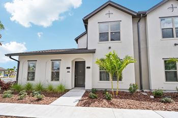 A white house with a black door and windows at The Hadley - North Port, FL Apartments, North Port 34287